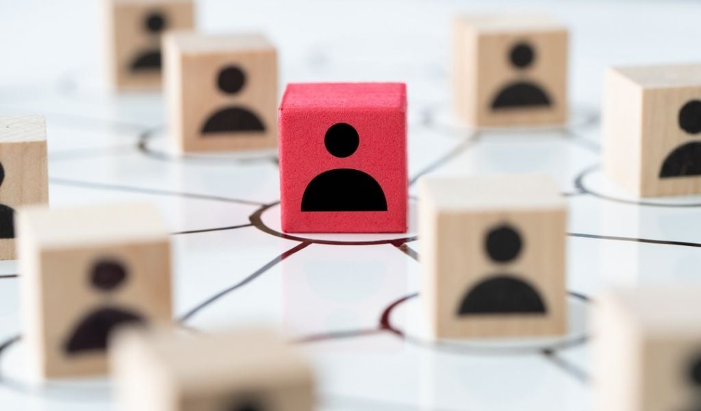 Assorted wooden blocks printed with human icons arranged on a grid, illustrating the connections between different types of expert.