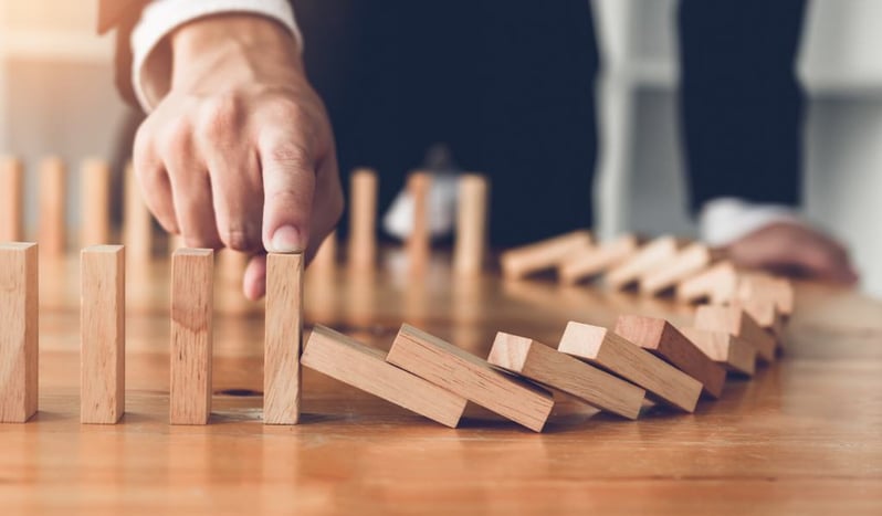 A businessman stopping dominoes falling