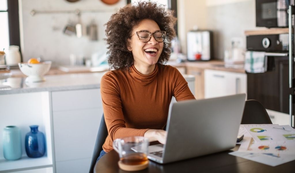 A person sitting in front of a laptop smiling